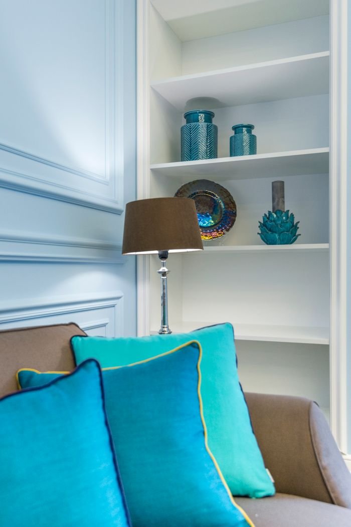 contact-img A stylish living room corner with vibrant throw pillows and elegant decor on the shelf.